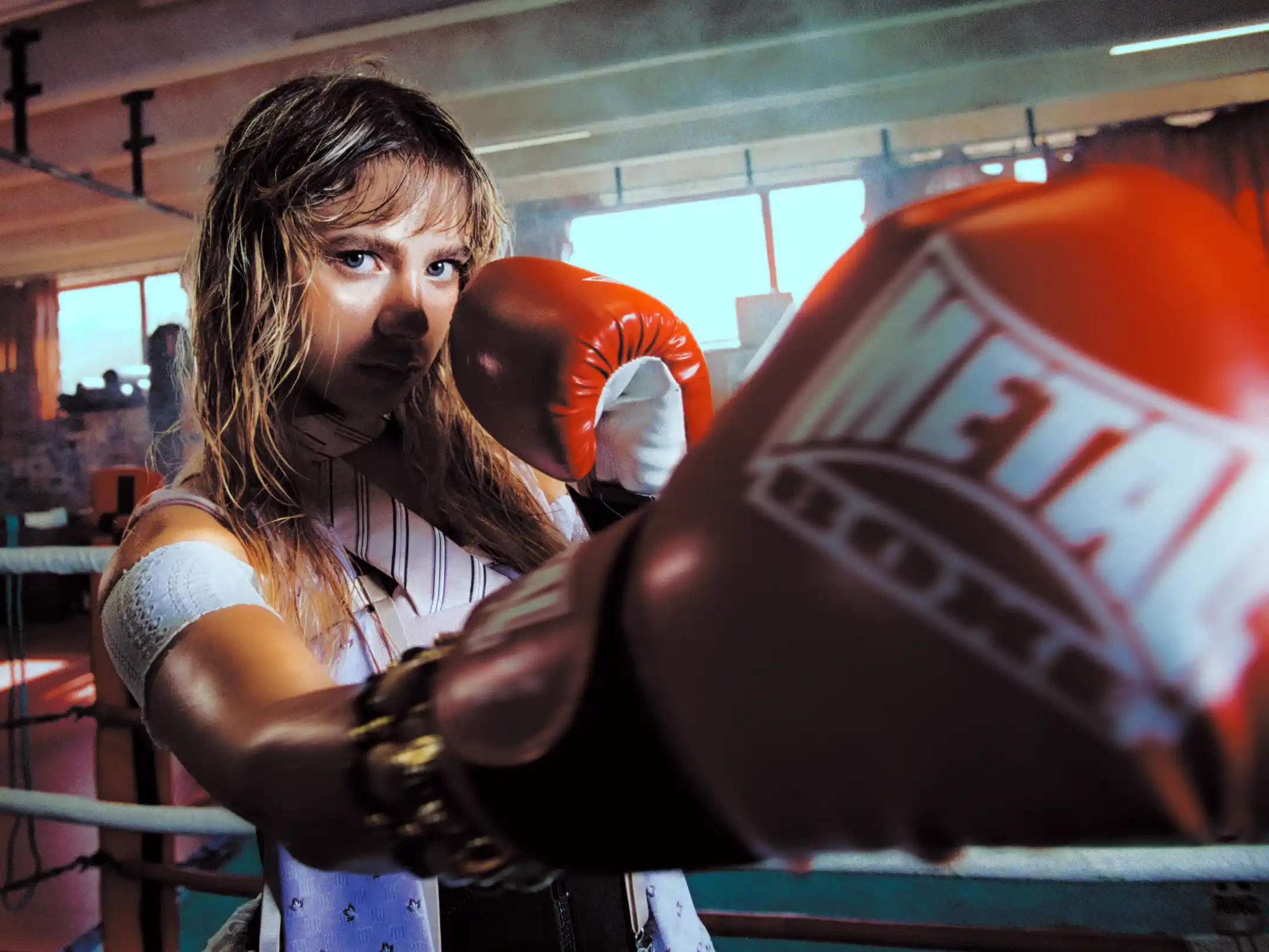 Wide-angle frame of Romane Parc's guard, one red glove pushed straight into the lens