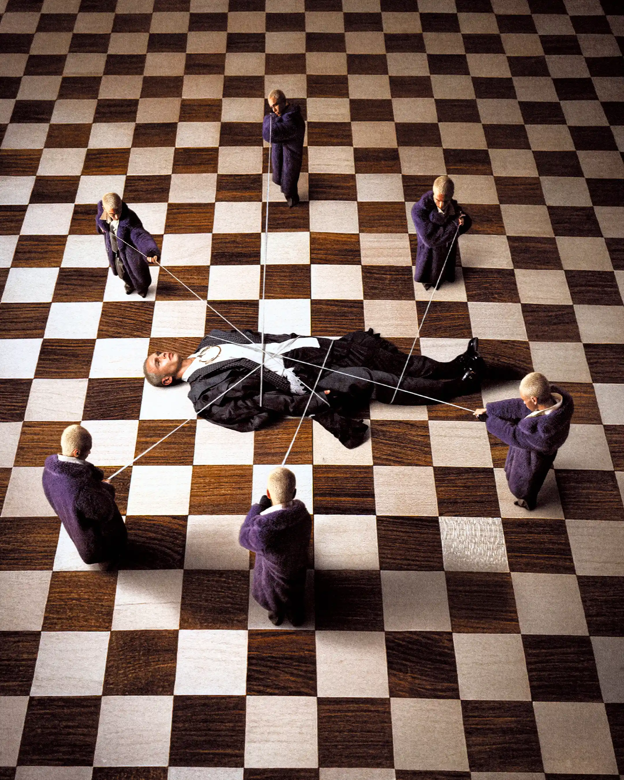 Overhead closing frame: six duplicates of Matheo pull strings around a body laid out on a checkerboard floor