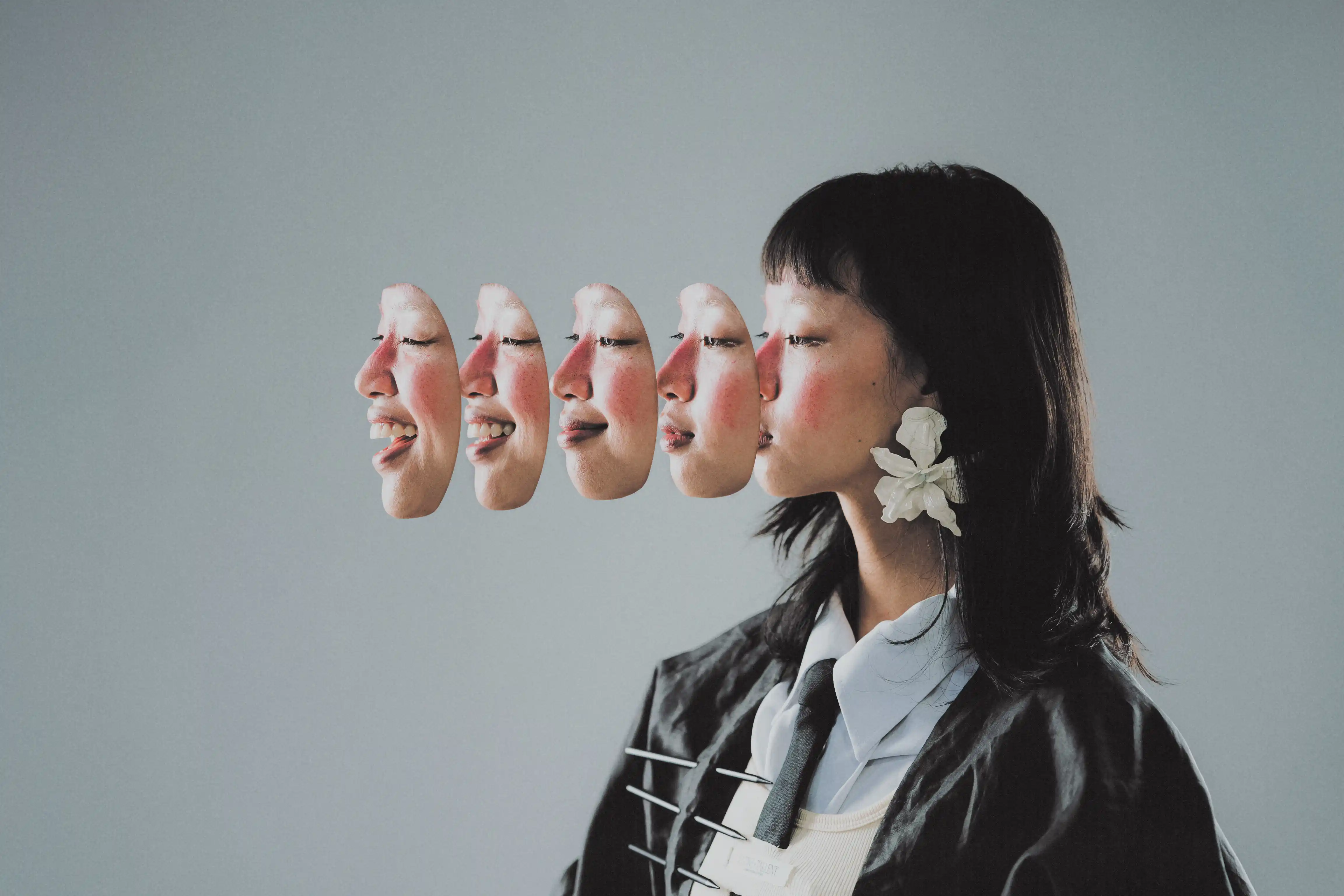 Profile of Karine P. with a trail of cut-out faces peeling away from her head, white flower at her ear