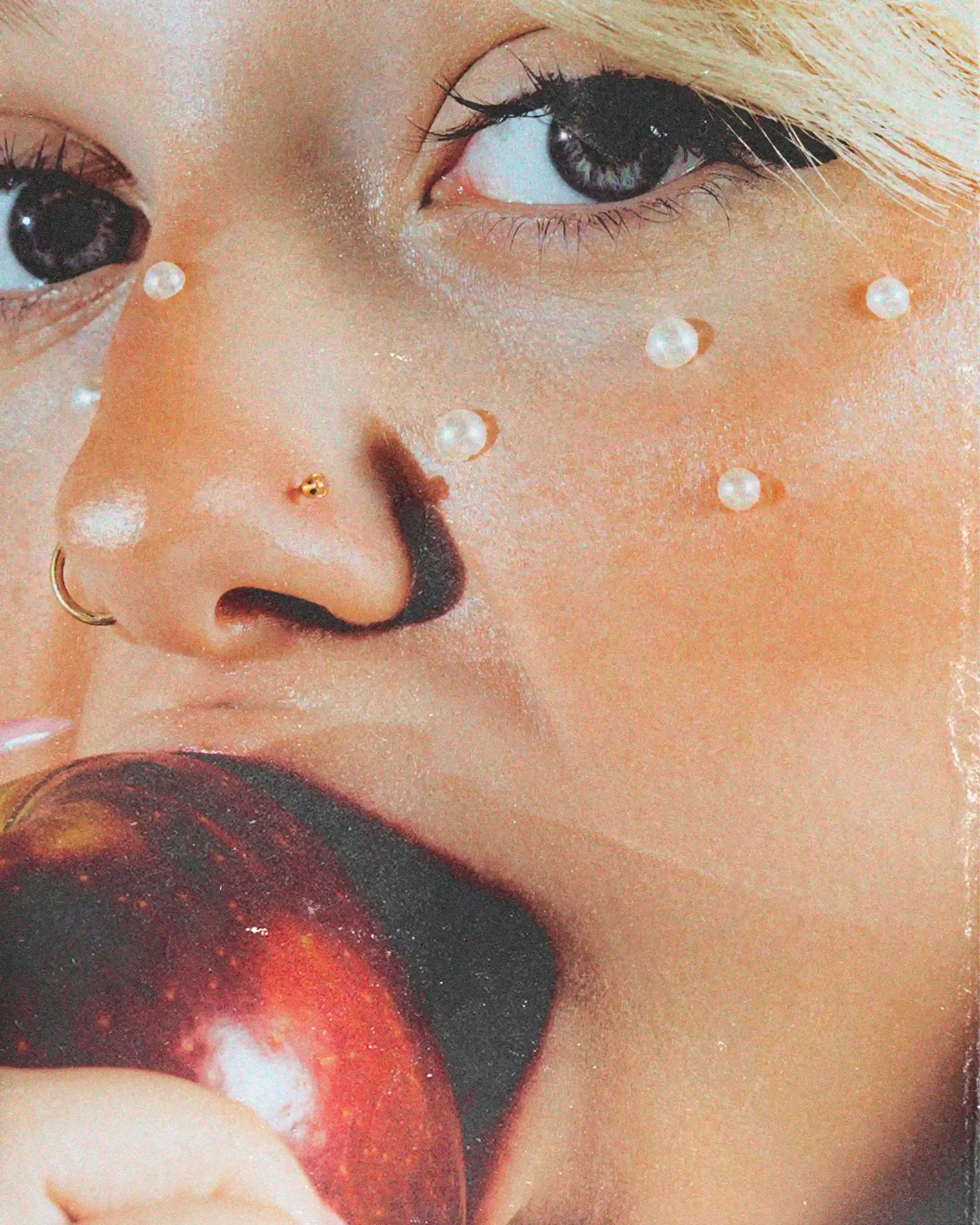 Extreme close-up on Julie's eyes and pearl-studded cheek as she bites into a red apple