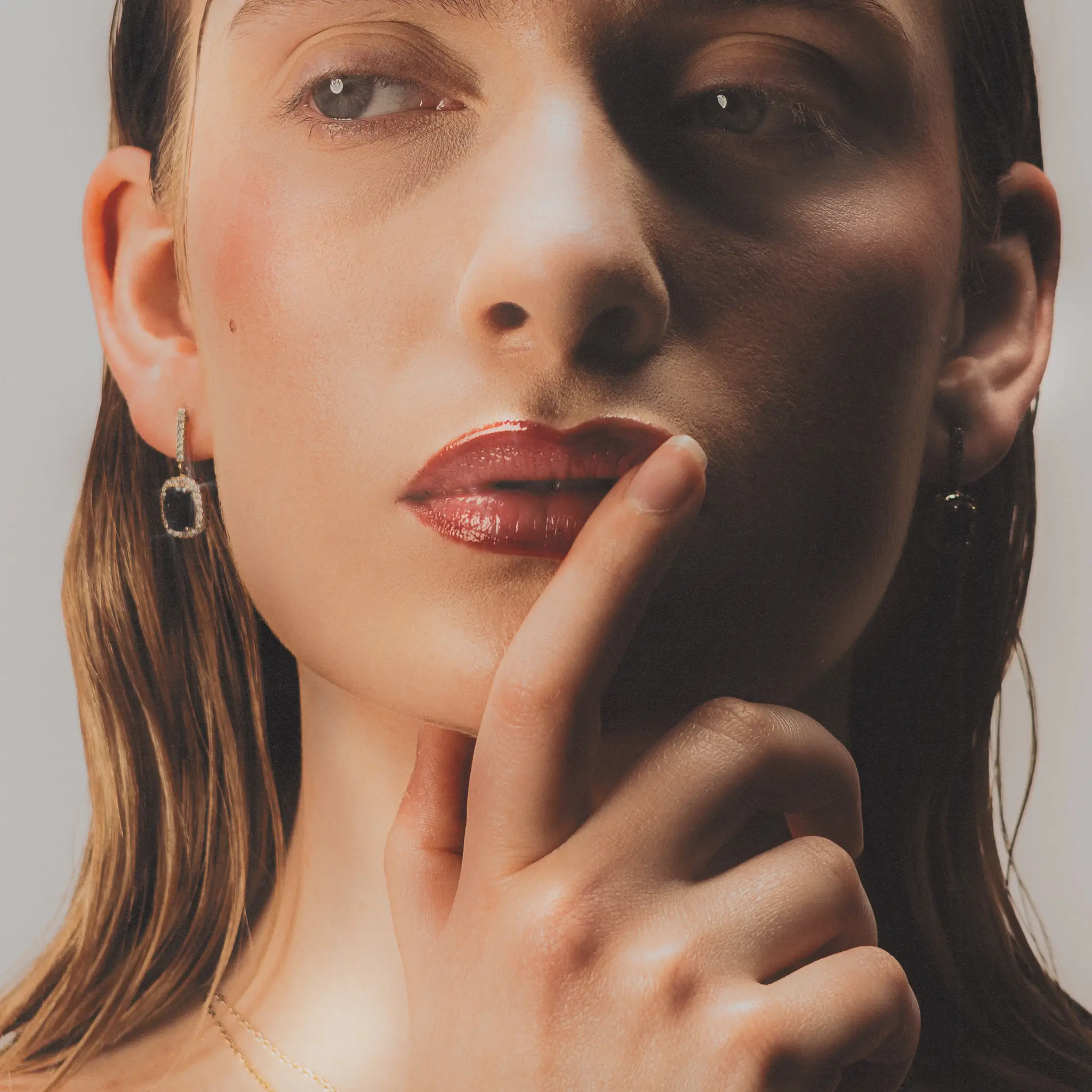 Tight beauty crop on Marine D., fingertip pressed against her lips as a hard shadow splits the frame