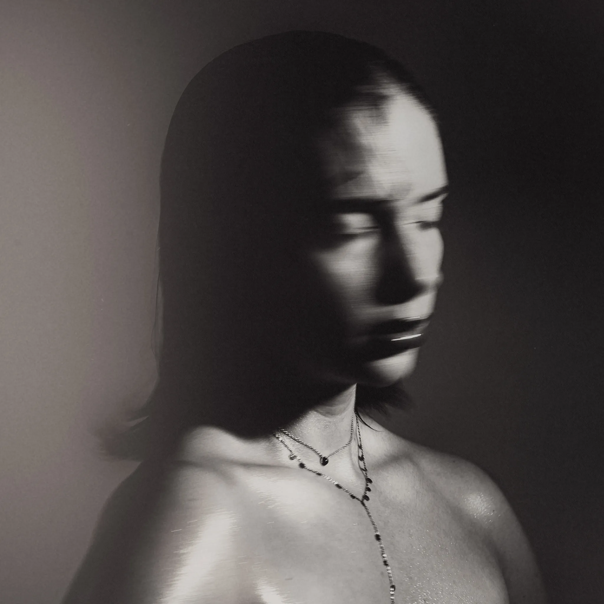 Marine D. with eyes closed, face half swallowed by shadow against the bare studio wall