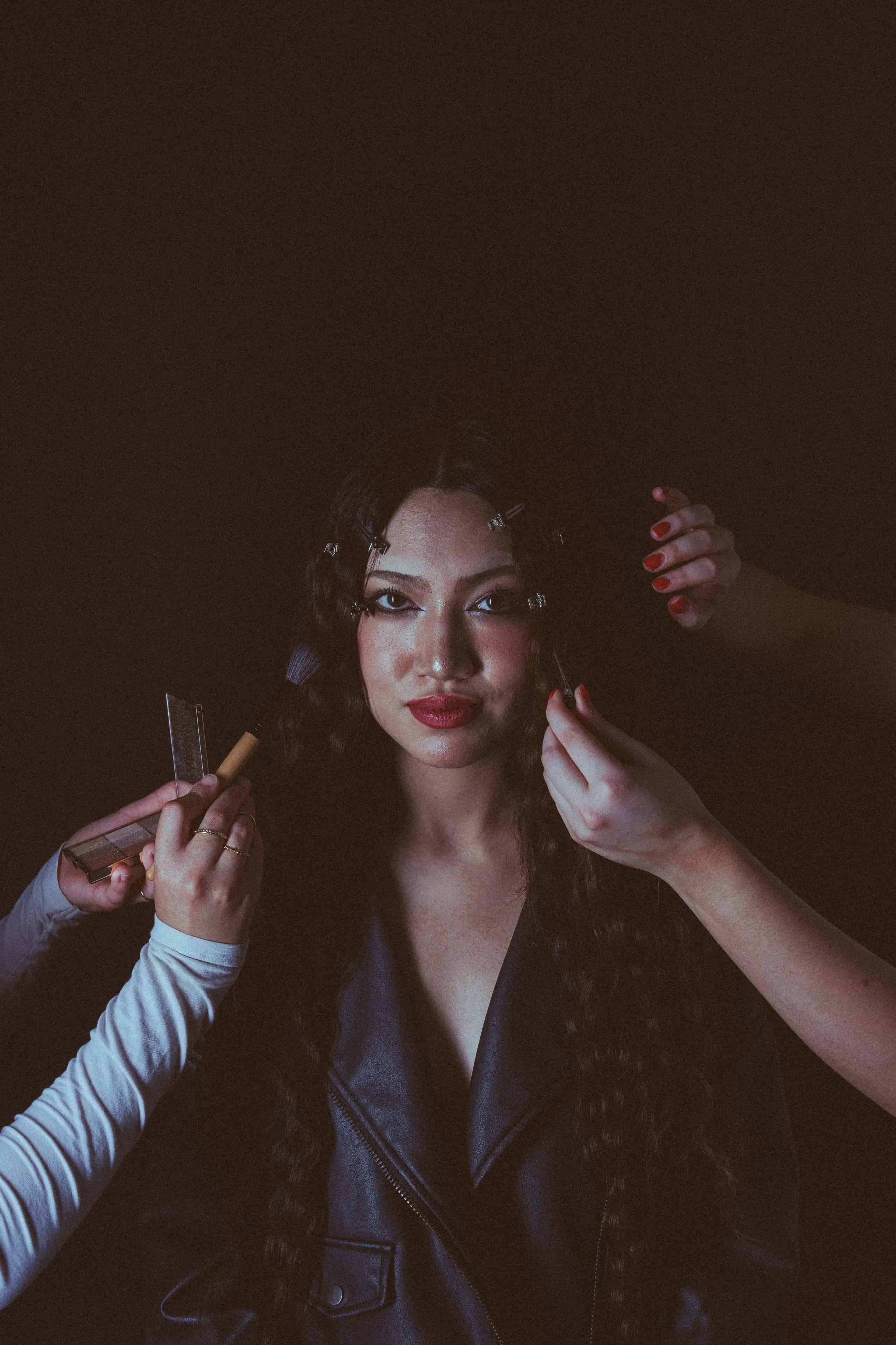 Miho S. holding the camera's gaze as an assistant's hands and a comb enter the frame